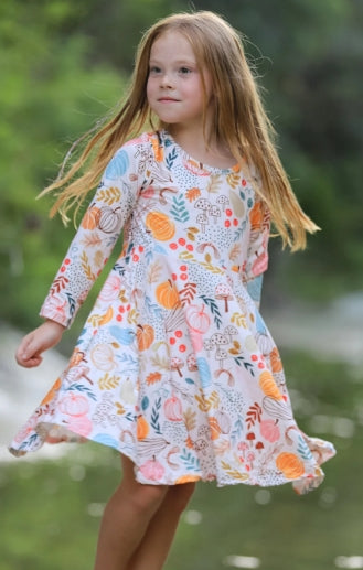 Child twirling outdoors in the long-sleeve pumpkin leaf print dress.