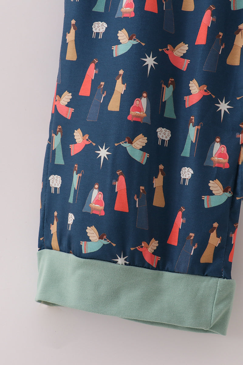 Close-up of the colorful Nativity print and mint-green cuff on navy pajama pants