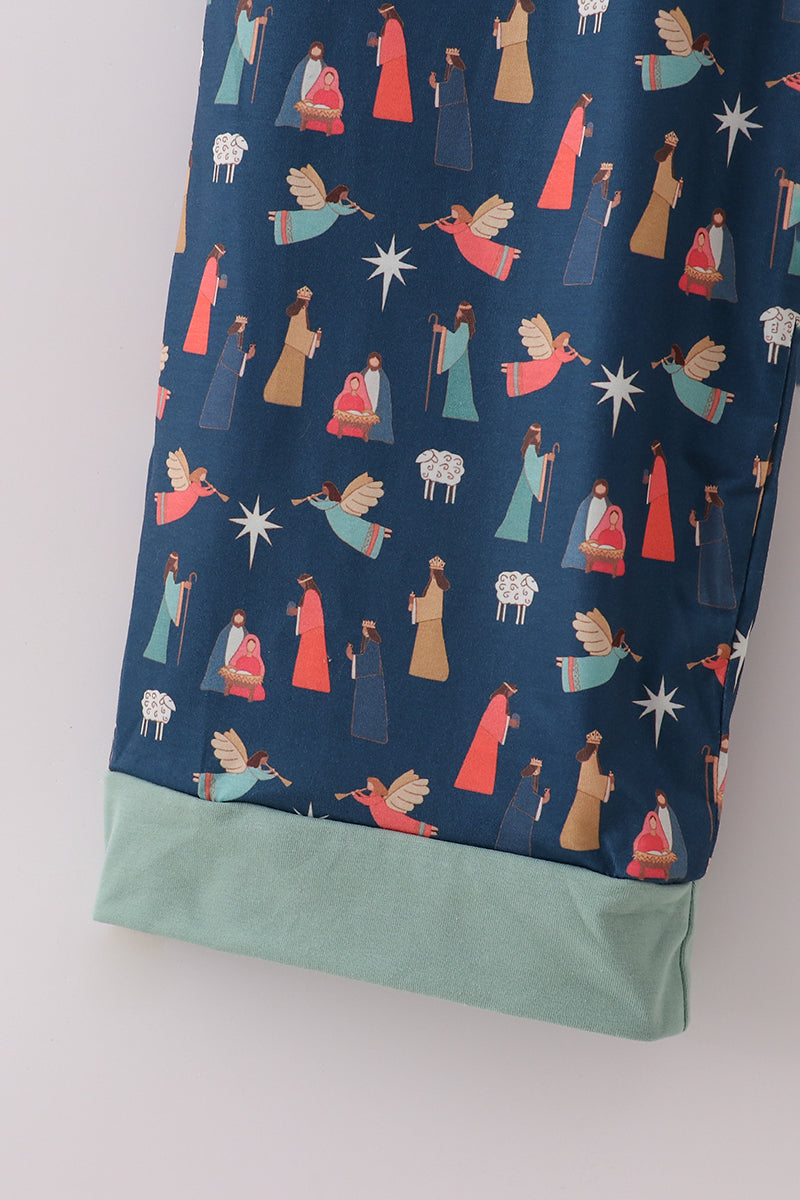 Close-up of the Nativity print and mint-green cuff on navy pajama pants