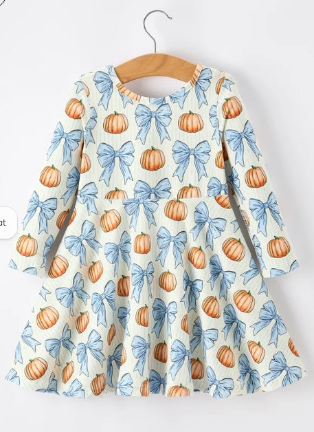 Front of long-sleeve girls dress with orange pumpkins and blue ribbon bows on a light background.