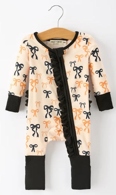 Front of bow-print baby girl zipper romper with black and peach-orange bows, black cuffs, and zipper ruffle.