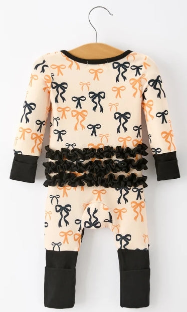 Back of bow-print baby girl romper with rows of black ruffles and contrasting black cuffs.