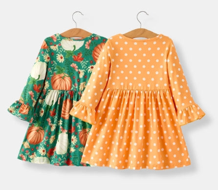 Back of Thanksgiving two-dress set with green pumpkin print and orange print dresses.