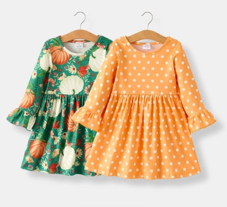 Front of green pumpkin-print dress and orange printed dress, both with long sleeves and ruffled cuffs.