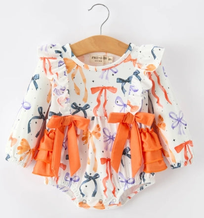 Front of long-sleeve bow-print baby romper with shoulder ruffles and bright orange waist bows.