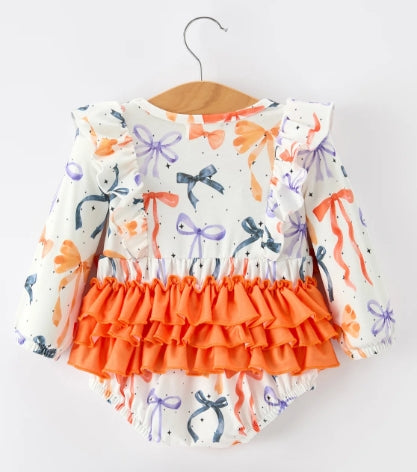 Back of Halloween bow-print baby romper with layered orange ruffles.