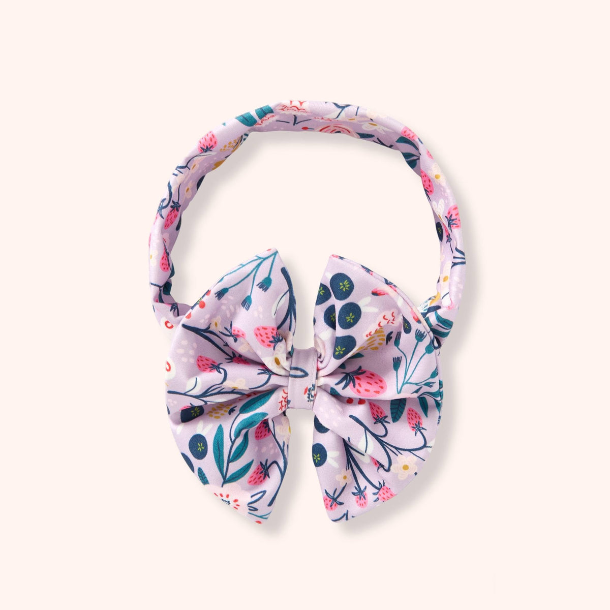 Pete & Lucy Blueberry Breeze bow headband with blueberries, pink strawberries, and leafy stems on a pale background.