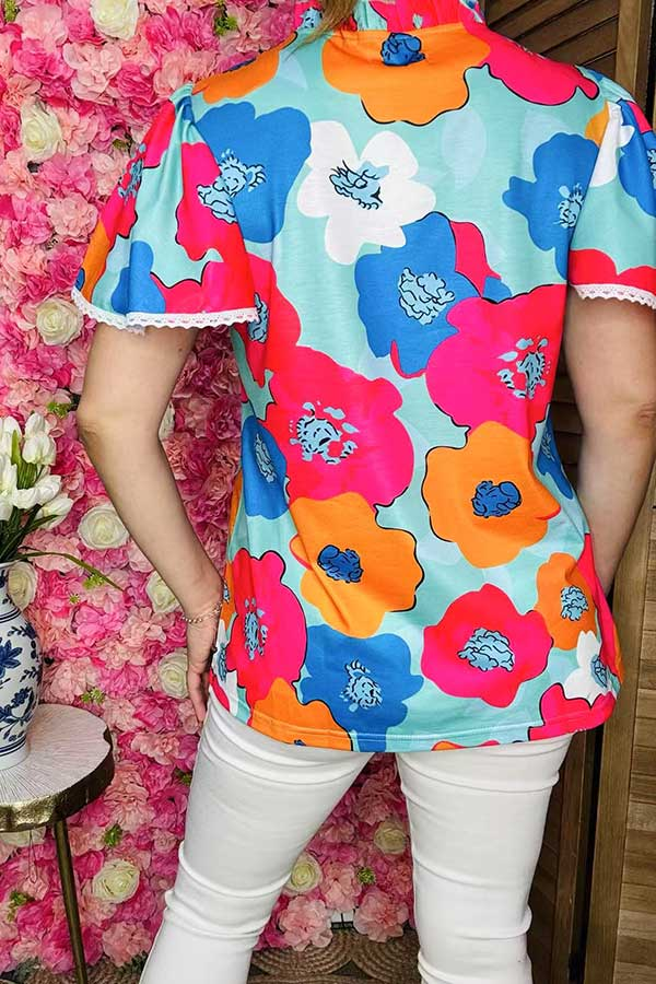 Back view of mint top with oversized pink, blue, orange, and white flowers.