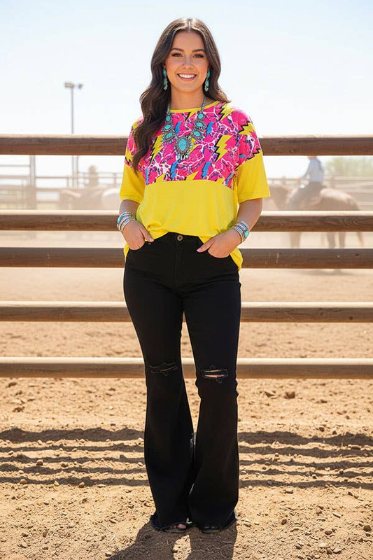 Woman wearing a yellow short-sleeve top with a pink multicolor lightning-print upper panel.