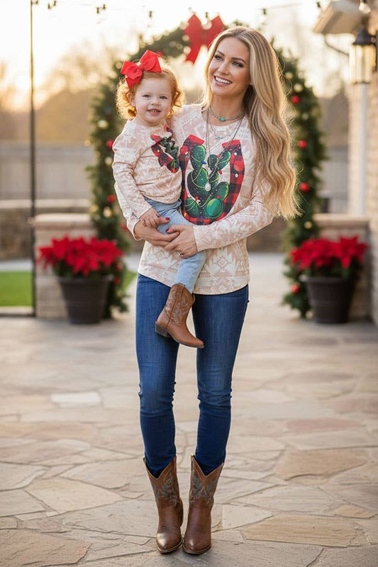 Woman wearing a light patterned horseshoe and cactus long-sleeve top while holding a child in a matching top; adult top sold separately.