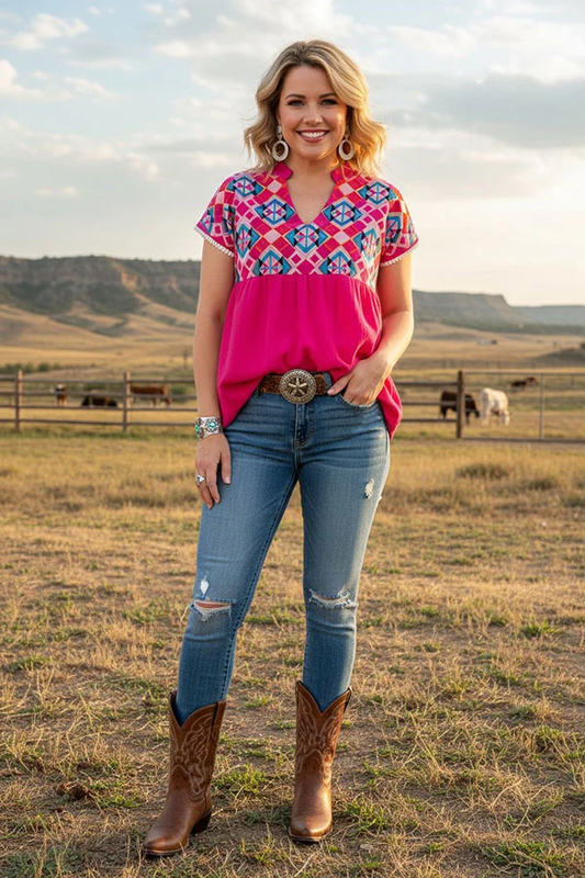 Woman wearing a hot pink Western Aztec embroidered short-sleeve top with jeans and boots.