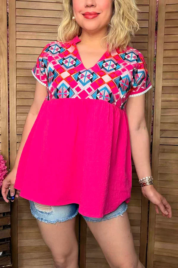 Front view of hot pink embroidered top with notched neckline and white sleeve trim.
