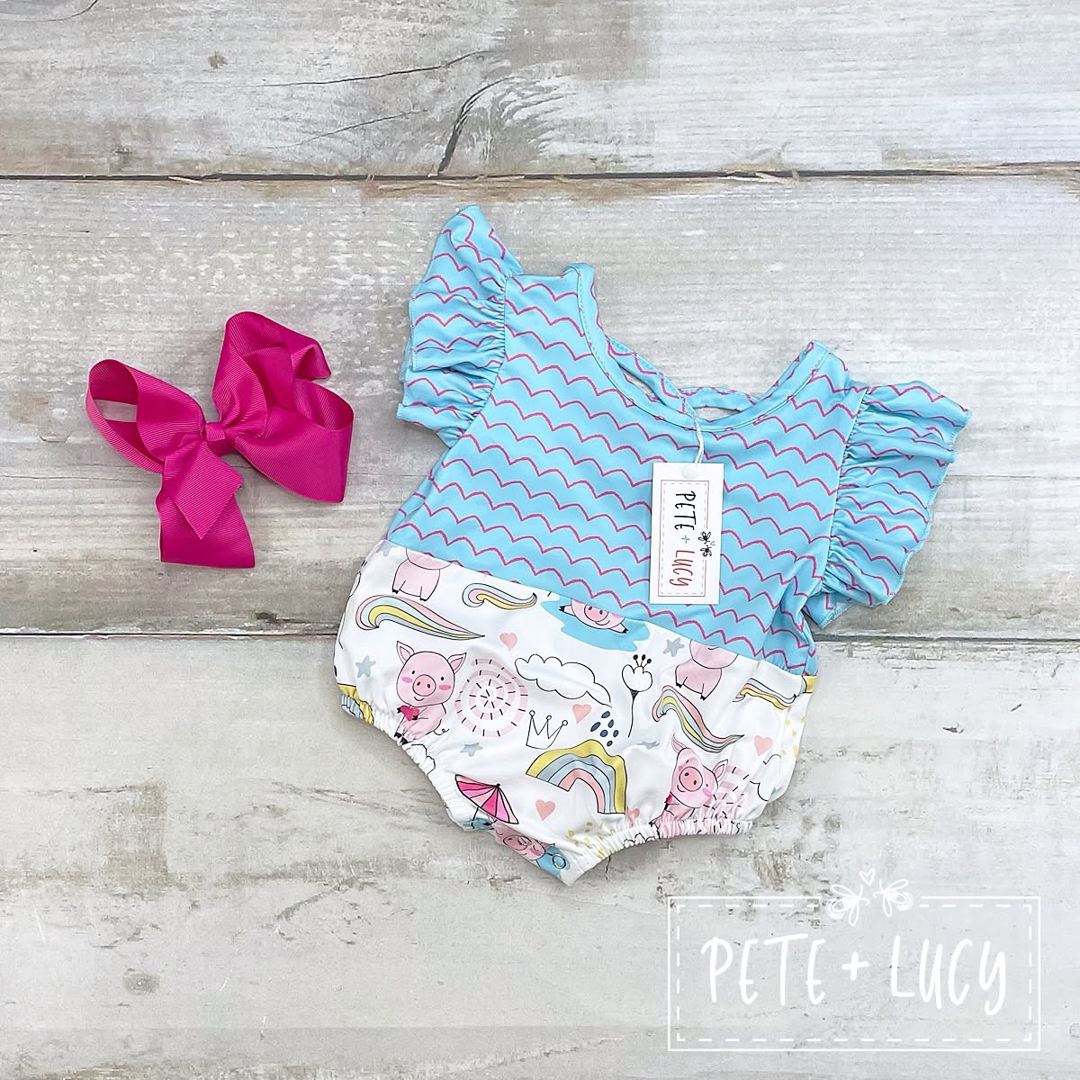 Pete + Lucy Piggy Party infant romper in blue and pig-and-rainbow print